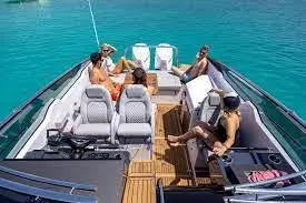 Four people relax on a luxury boat surrounded by turquoise water, enjoying a sunny day with comfortable seating.